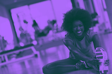 Image showing woman in a gym stretching and warming up man in background worki