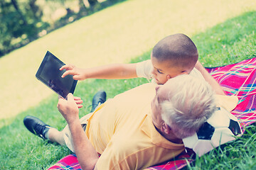 Image showing grandfather and child in park using tablet