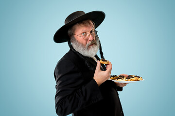 Image showing The senior orthodox Jewish man with black hat with Hamantaschen cookies for Jewish festival of Purim