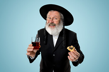 Image showing The senior orthodox Jewish man with black hat with Hamantaschen cookies for Jewish festival of Purim