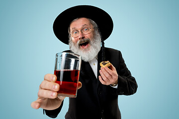Image showing The senior orthodox Jewish man with black hat with Hamantaschen cookies for Jewish festival of Purim
