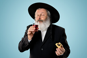 Image showing The senior orthodox Jewish man with black hat with Hamantaschen cookies for Jewish festival of Purim