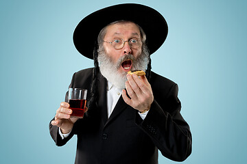 Image showing The senior orthodox Jewish man with black hat with Hamantaschen cookies for Jewish festival of Purim