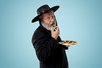Image showing The senior orthodox Jewish man with black hat with Hamantaschen cookies for Jewish festival of Purim