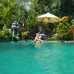 Image showing Happy couple kissing while relaxing in outdoor spa infinity swimming pool surrounded with lush tropical greenery of Ubud, Bali. Luxury spa and wellness vacation retreat concept