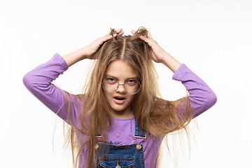 Image showing Long-haired girl scratches her head with her hands