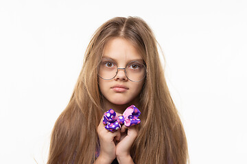 Image showing Closeup portrait of a scared girl with a blue bow in her hands