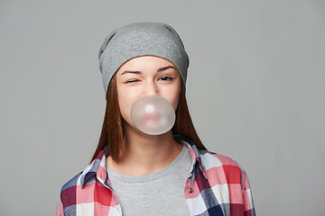 Image showing Smiling teen girl blowing bubblegum winking at you