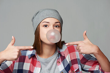 Image showing Closeup of cheeky teen girl blowing bubblegum and pointing at it