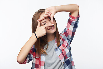 Image showing Smiling teen girl looking at camera through finger frame