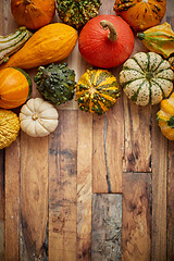 Image showing Autumn background. Small multi colored pumpkins on a wooden table. Top view, with copy space