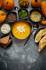 Image showing Delicious pumpkin soup with cream, seeds, bread and fresh herbs 