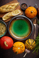 Image showing Empty ceramic bowl and ingredients ready for pumpkin soup. With different kinds of small pumpkins