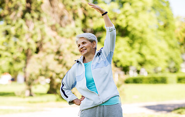 Image showing happy senior woman exercising at summer park