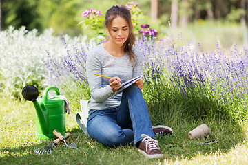 Image showing young woman writing to notebook at summer garden