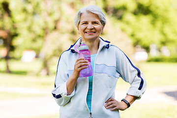 Image showing sporty senior woman with bottle of water at park