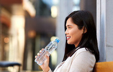 Image showing woman drinking water sitting on wooden city bench