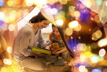 Image showing happy family reading book in kids tent at home