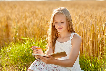 Image showing smiling girl writing to diary on cereal field