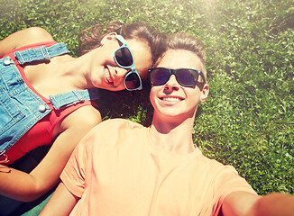 Image showing happy teenage couple taking selfie on summer grass