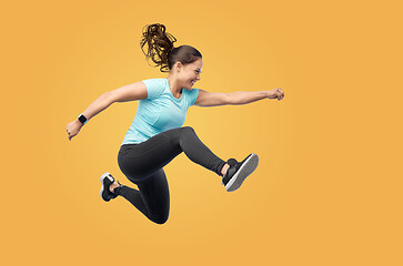 Image showing happy fit young woman jumping in air