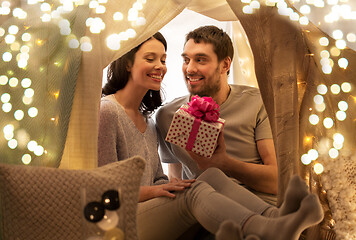 Image showing happy couple with gift box in kids tent at home