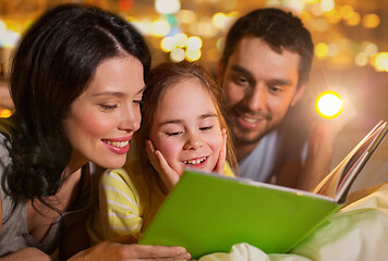 Image showing happy family reading book in bed at night at home