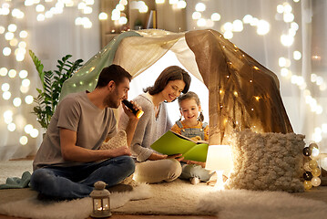 Image showing happy family reading book in kids tent at home