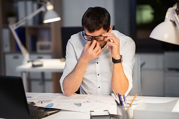 Image showing tired businessman working at night office