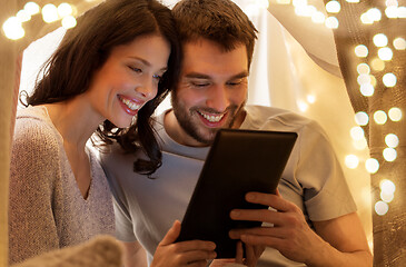 Image showing happy couple with tablet pc in kids tent at home