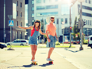 Image showing teenage couple riding skateboards on city street