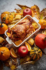 Image showing Thanksgiving dinner table with roasted whole chicken or turkey, pumpkin, baked potatoes, chestnuts