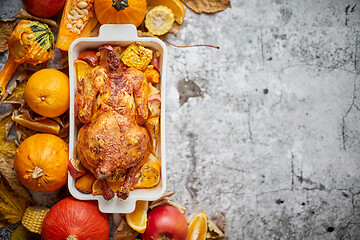 Image showing Thanksgiving dinner table with roasted whole chicken or turkey, pumpkin, baked potatoes, chestnuts