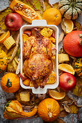 Image showing Thanksgiving dinner table with roasted whole chicken or turkey, pumpkin, baked potatoes, chestnuts