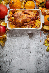 Image showing Festive chicken baked by Thanksgiving on white owen plate and a harvest of seasonal vegetables