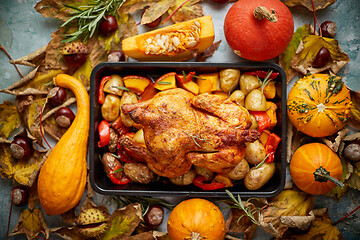 Image showing Roasted chicken or turkey garnished with pumpkins, pepper and potatoes. Served on a rustic table