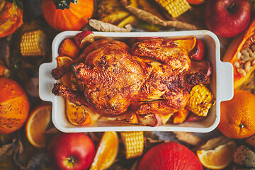 Image showing Festive chicken baked by Thanksgiving on white owen plate and a harvest of seasonal vegetables