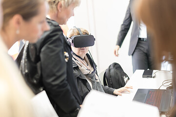 Image showing Unrecognizable woman wearing virtual reality headset glasses on virtual reality trade show business conference presentation