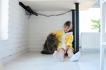 Image showing Punished girl sitting under the table and stroking a domestic cat