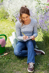 Image showing young woman writing to notebook at summer garden