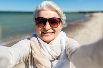 Image showing senior woman in sunglasses taking selfie on beach