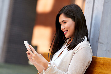 Image showing asian woman using smartphone sitting on bench