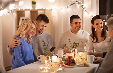 Image showing happy family with smartphone at tea party at home