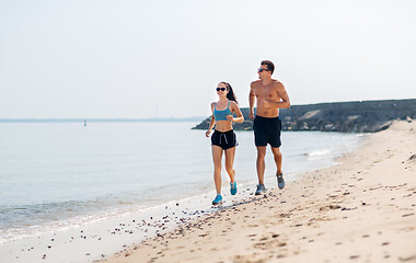 Image showing couple in sports clothes running along on beach