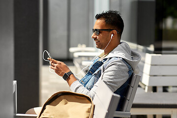 Image showing man with earphones and smartphone on city street