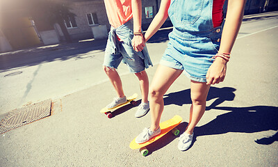 Image showing teenage couple riding skateboards on city street