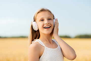 Image showing happy girl in headphones on cereal field in summer