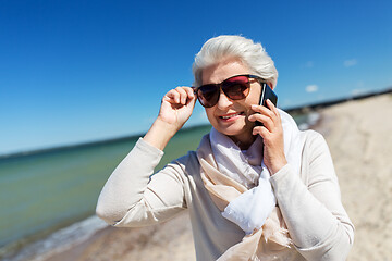 Image showing senior woman calling on smartphone on beach