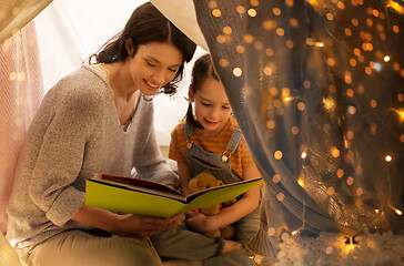 Image showing happy family reading book in kids tent at home