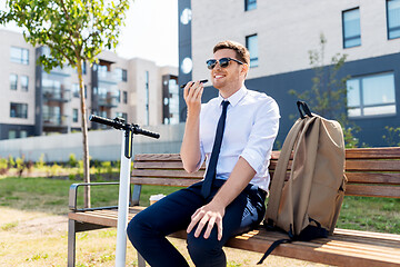 Image showing businessman recording voice message by smartphone